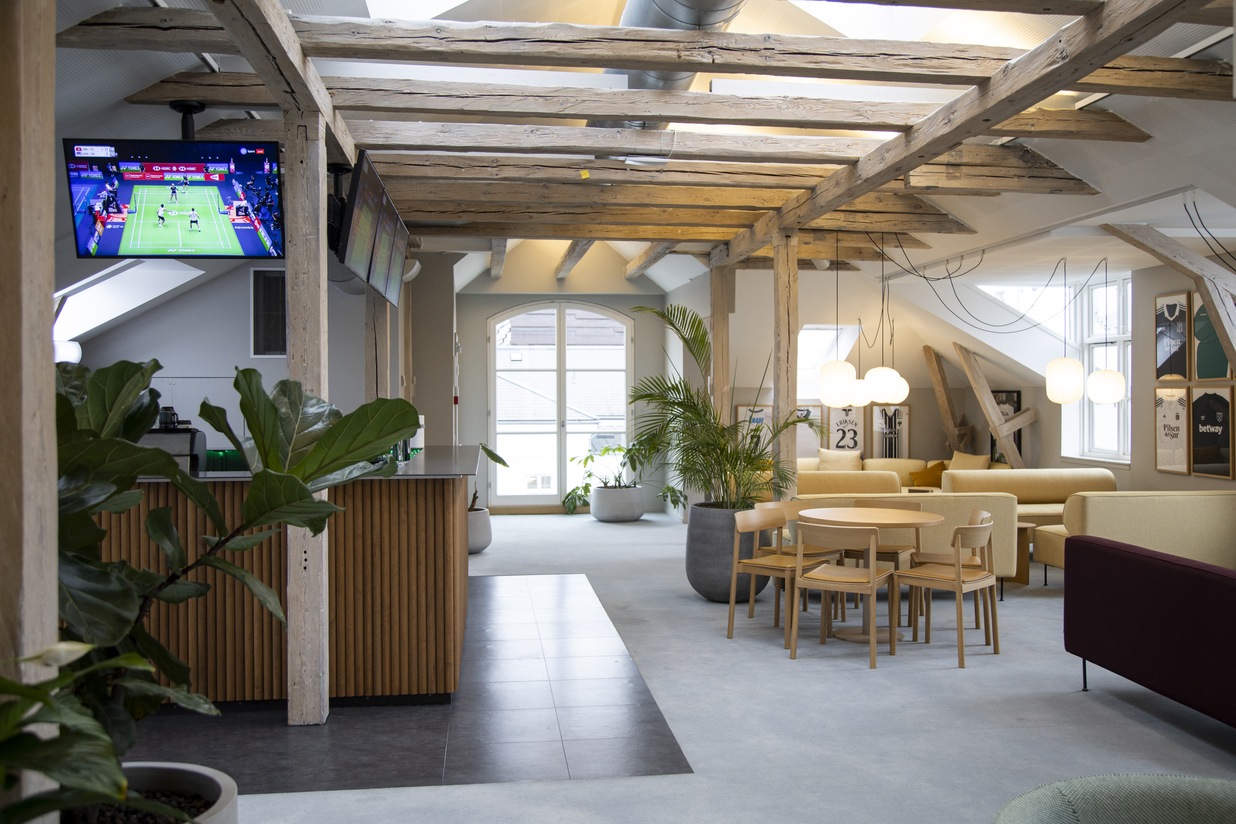 Åbne fællesområder med integrerede AV‑skærme og moderne design, der understøtter sociale zoner, events og uformel kommunikation.