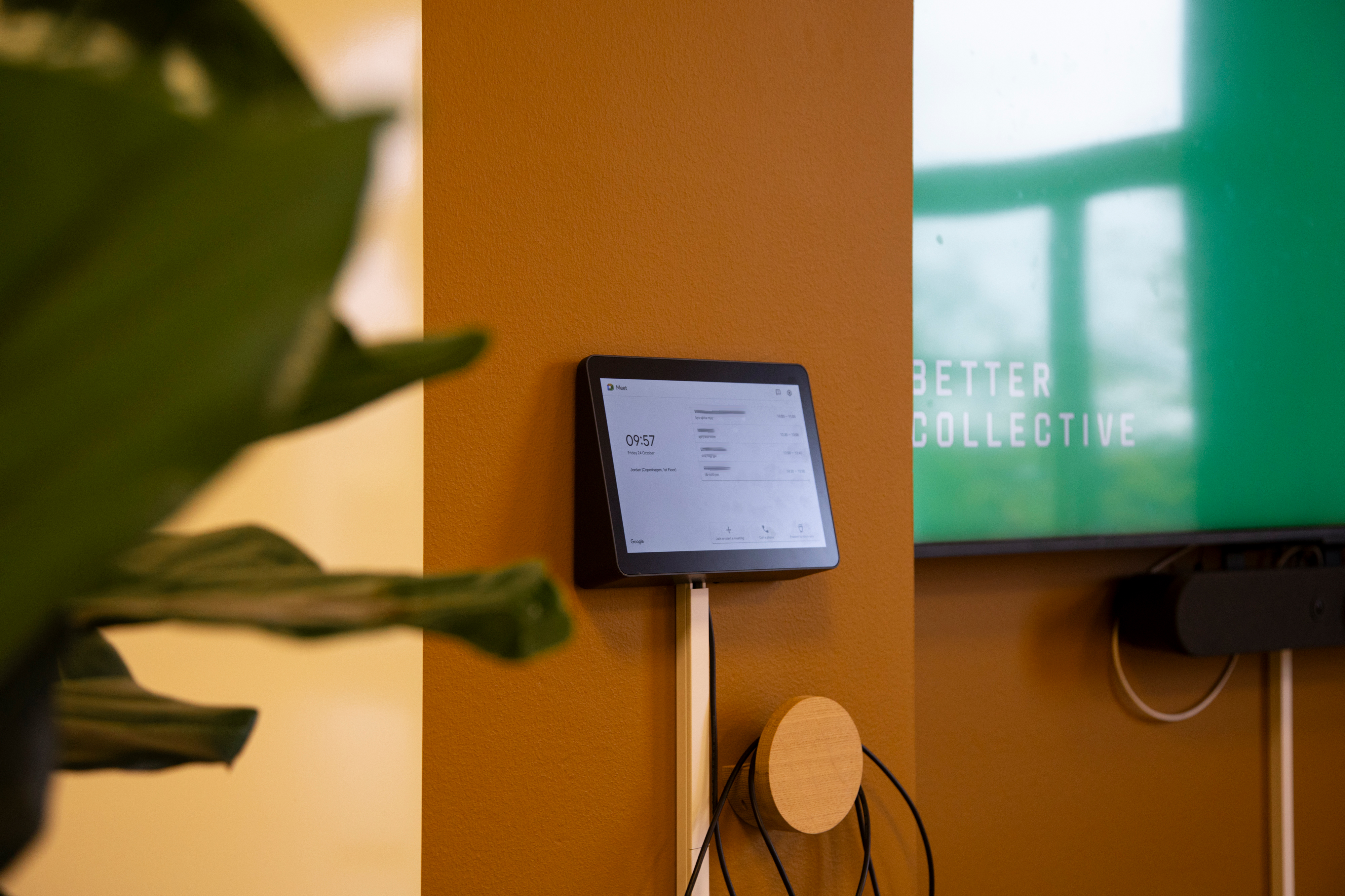 Modern office reception with a living green wall and large digital display at Better Collective.