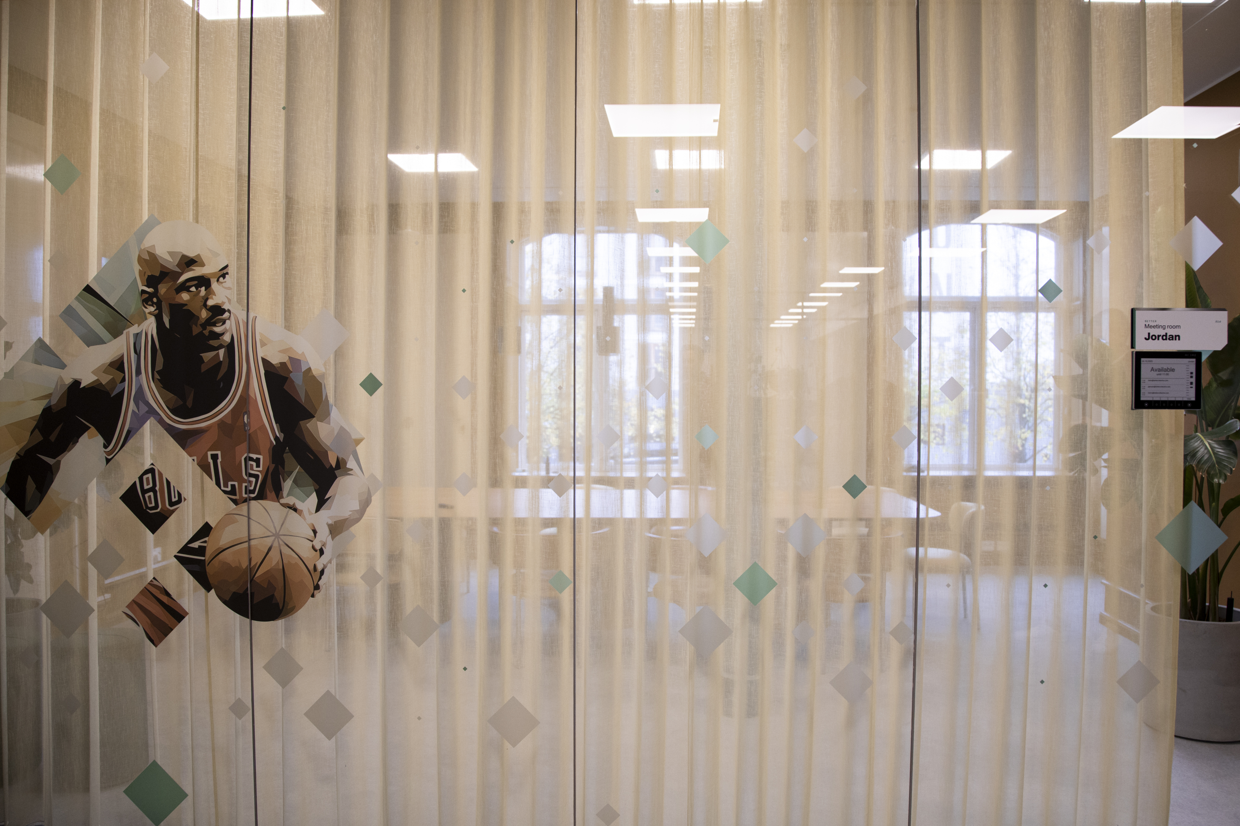 Glass‑fronted meeting room with sports‑themed artwork and soft, diffused lighting.