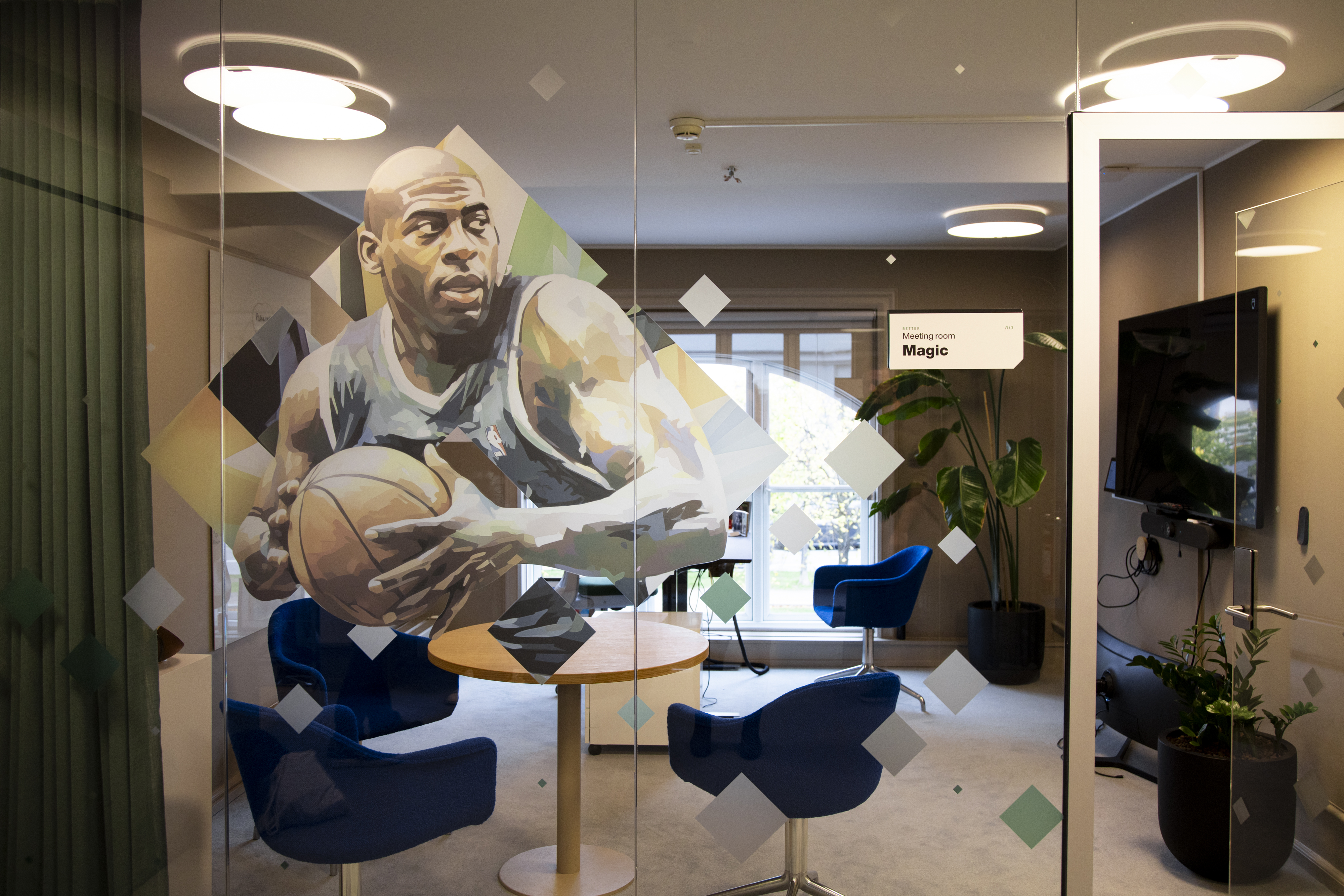 Modern meeting room with sports‑themed glass artwork, blue seating and contemporary décor.