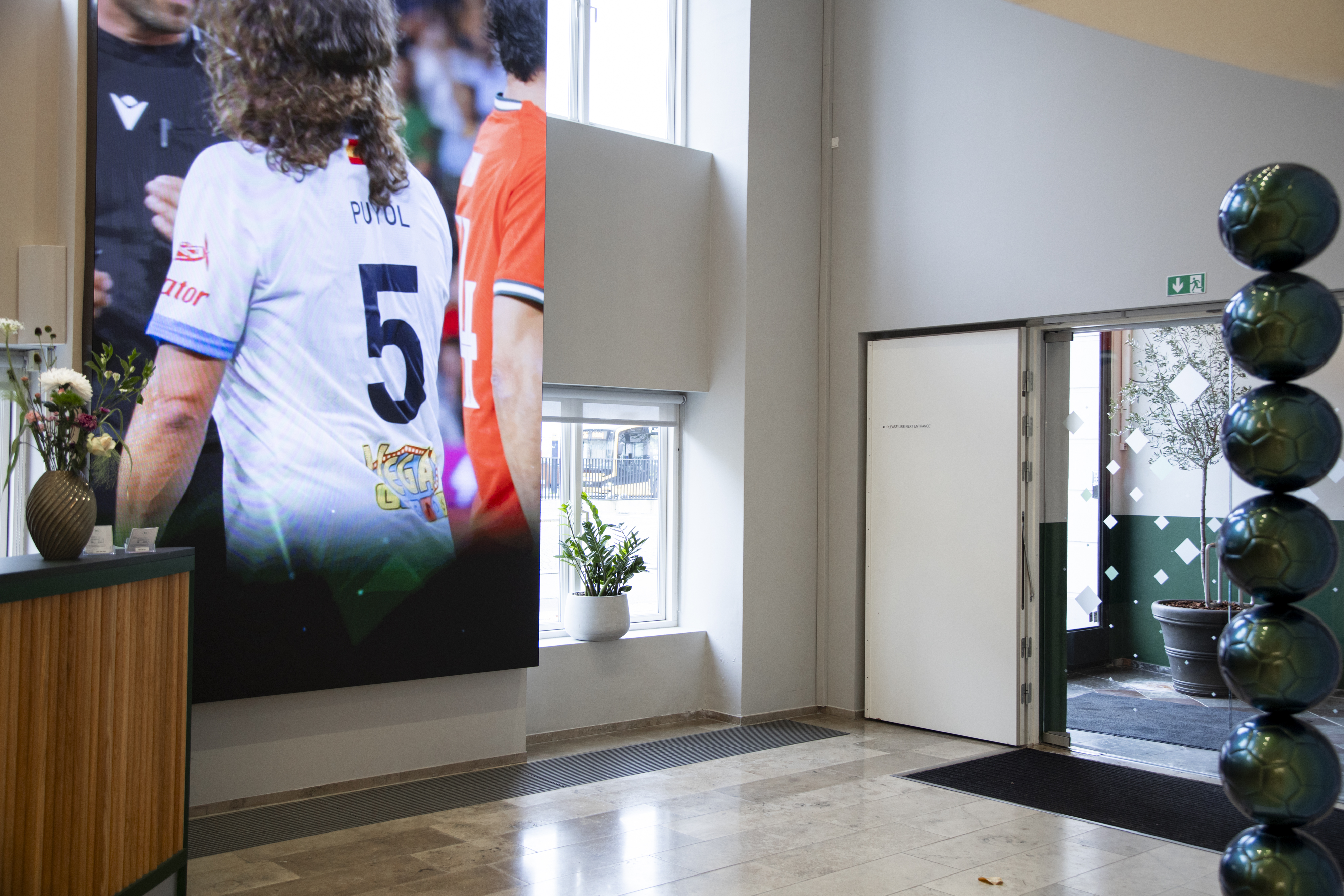 Bright office entrance featuring a large digital display and modern décor.