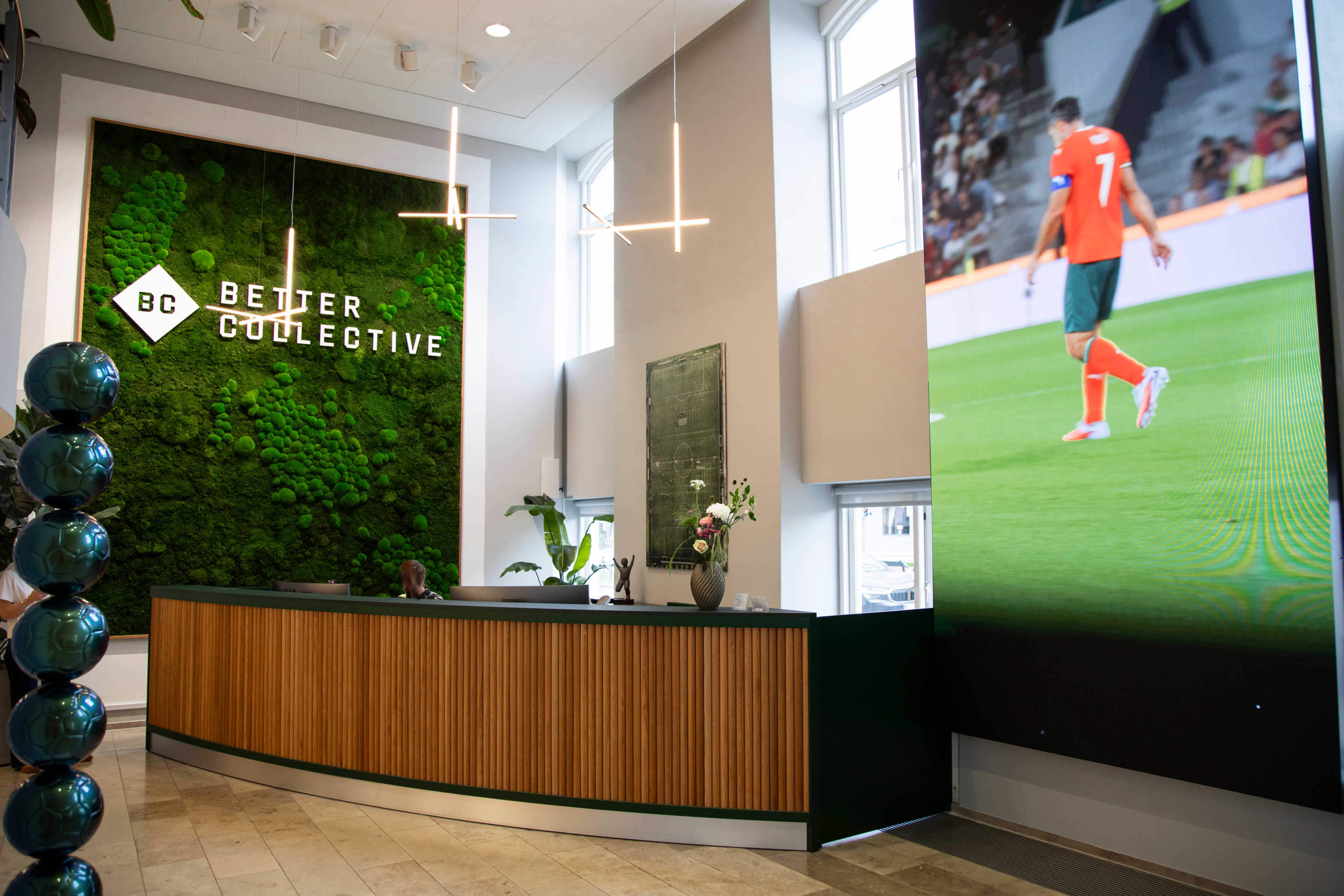 Modern reception area at Better Collective featuring a green living wall and digital display.
